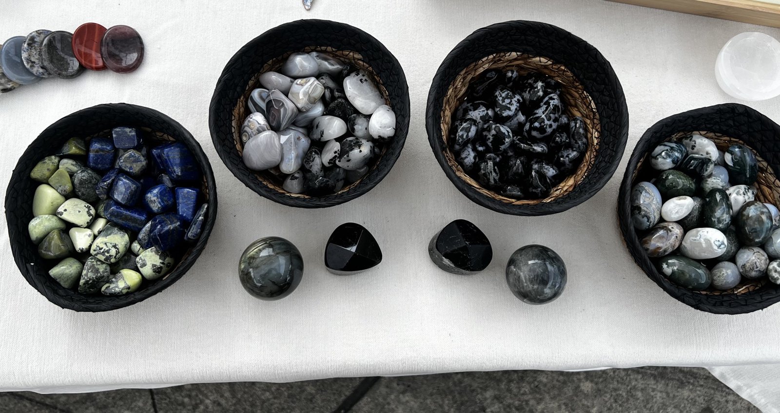 Baskets of tumbled crystals and polished spheres on a market table